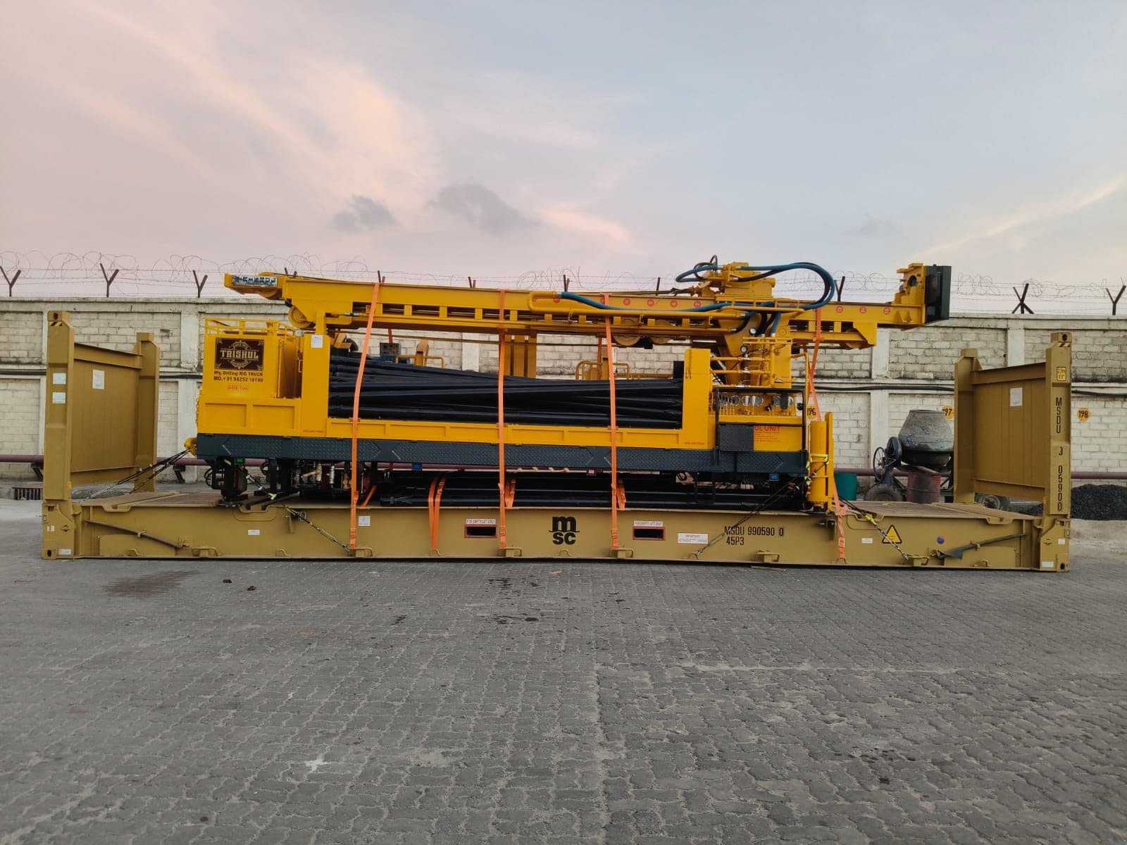 Over-dimensional drilling rig secured on a flat-rack container